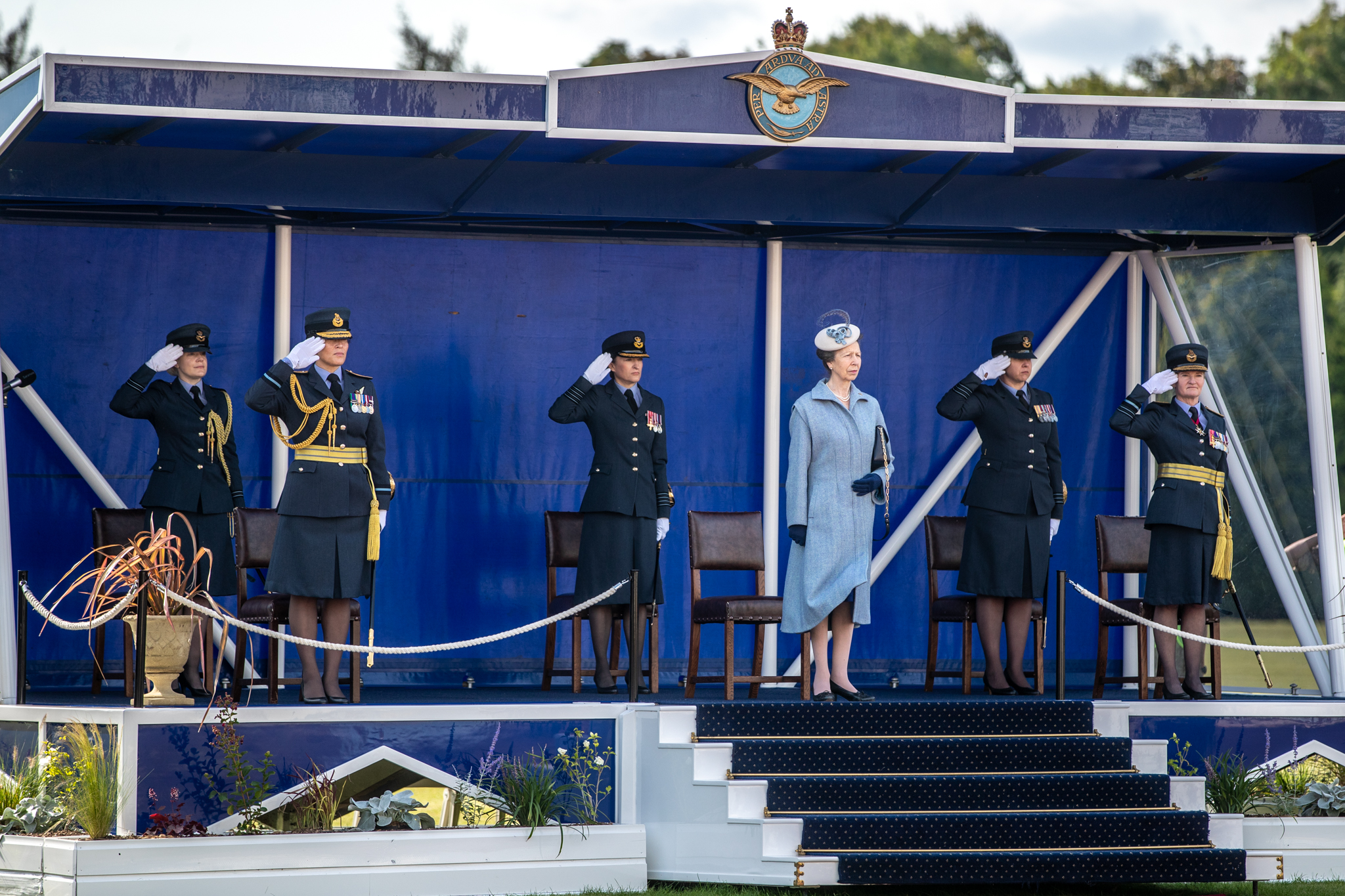 Her Royal Highness stands on parade stage with personnel.